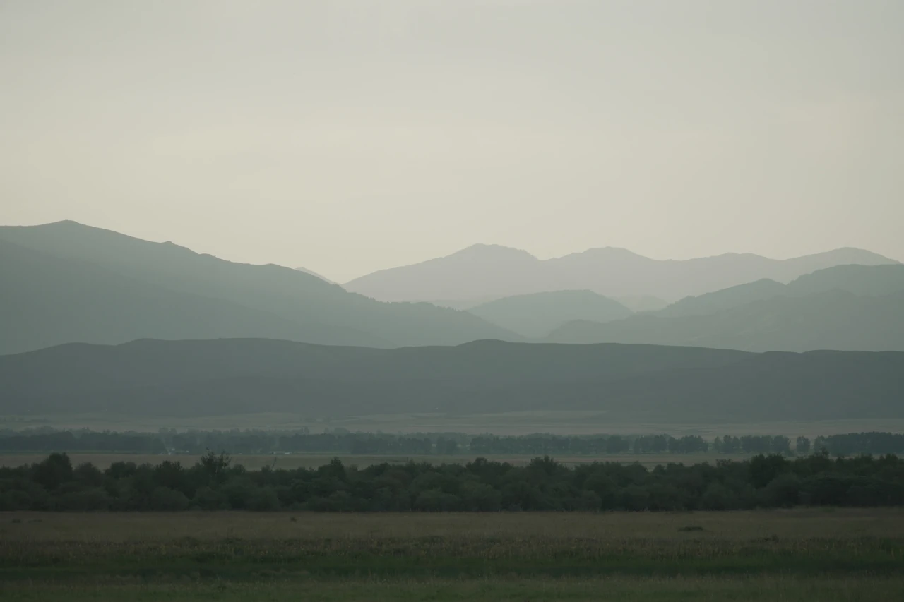 Layers of mountains receding into haze beyond an open plain.