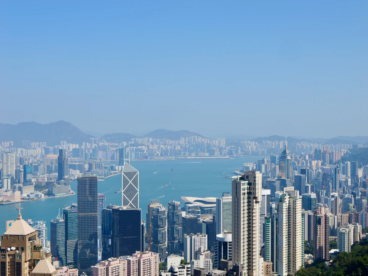 High-rise buildings around a harbour with mountains beyond.