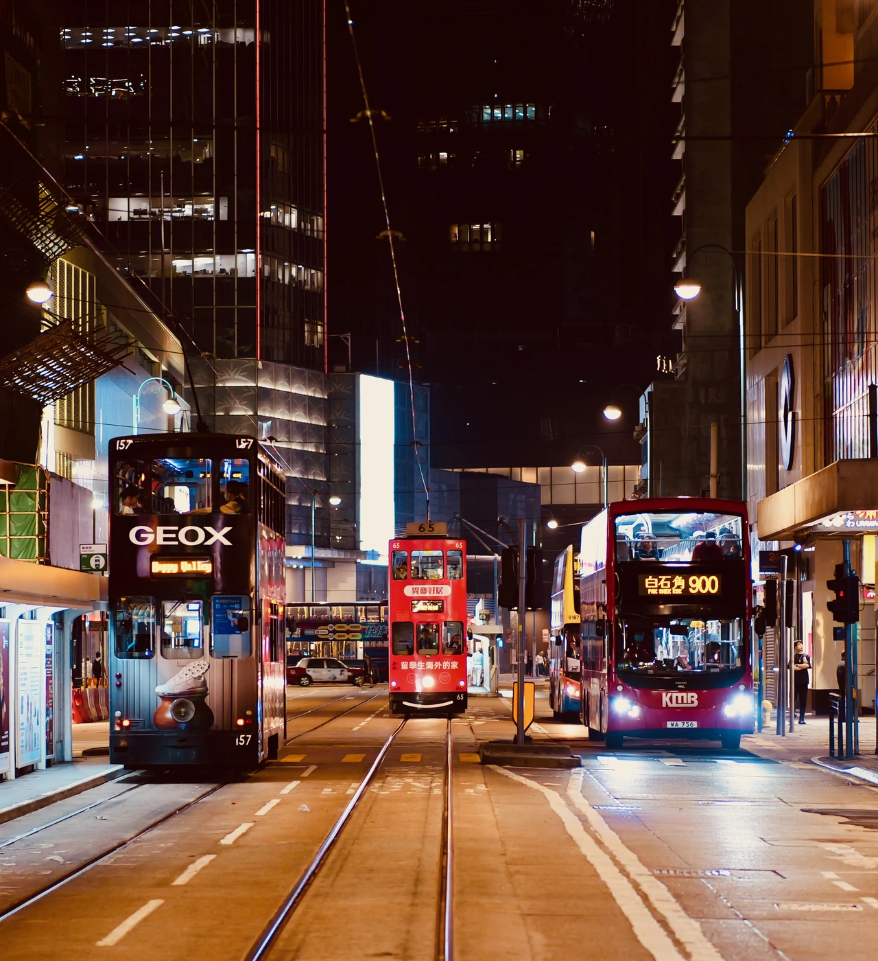 A tram between illuminated shops at night.