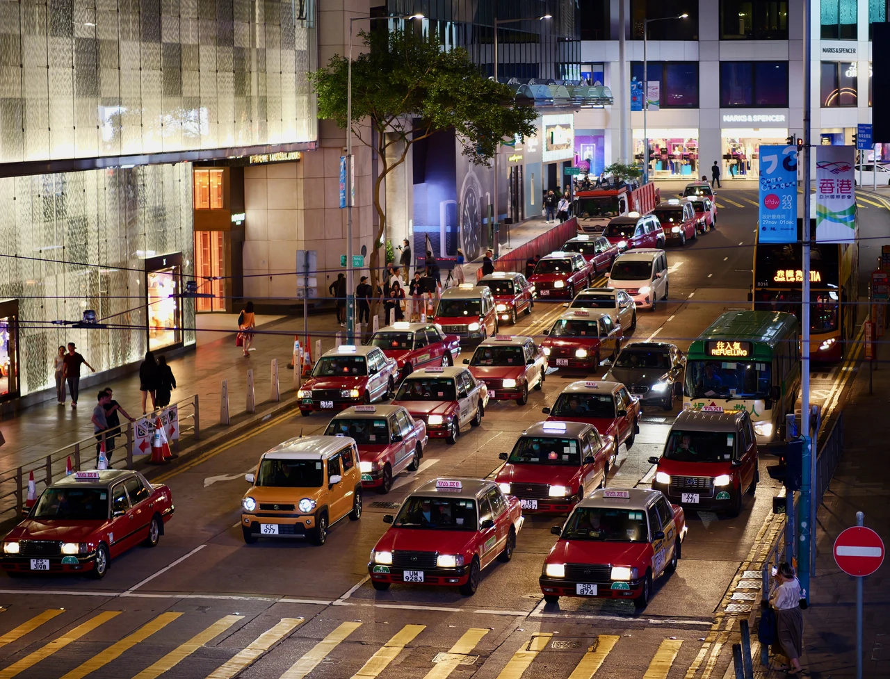 Dense traffic and trams beneath illuminated city signs.