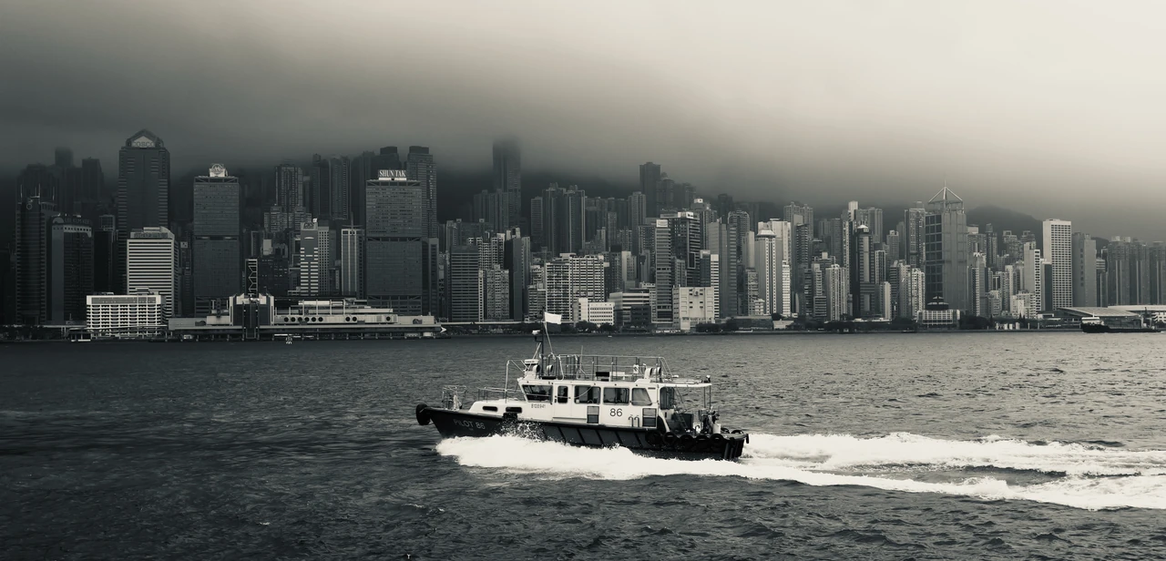 A boat passing a skyline beneath low clouds.