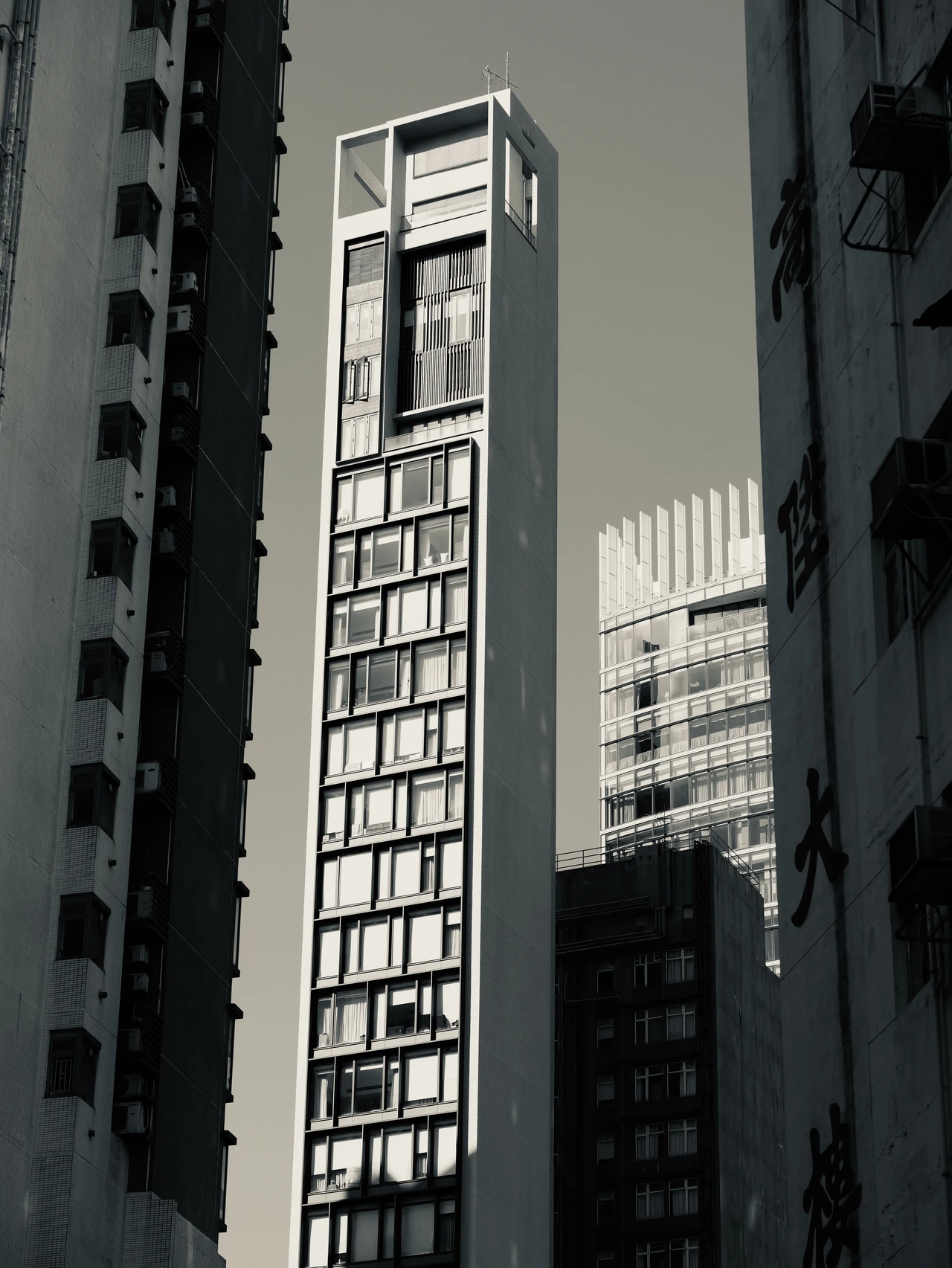 A narrow sunlit building between darker neighbouring facades.