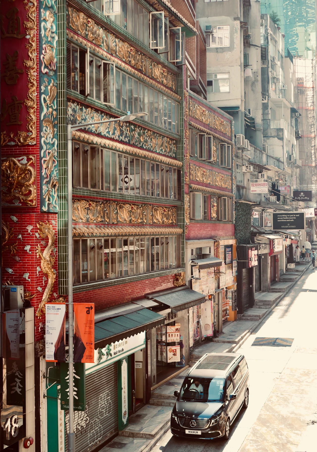 Signs, windows and balconies along a narrow urban street.